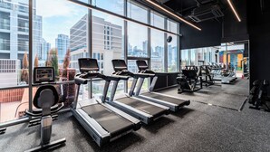 Een moderne sportschool met loopbanden, hometrainers en krachttoestellen. Grote ramen bieden uitzicht op de stadsgezicht.