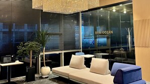 Een modern interieur met een grote, geometrische kroonluchter, een zithoek met kussens en een groot raam met uitzicht op de stad.