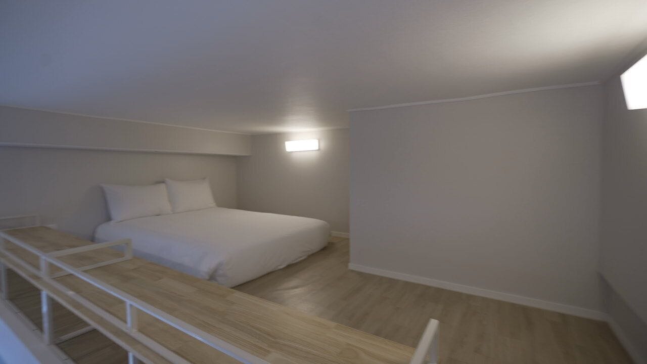 A bedroom with a bed, a wooden bench, and a nightstand.
