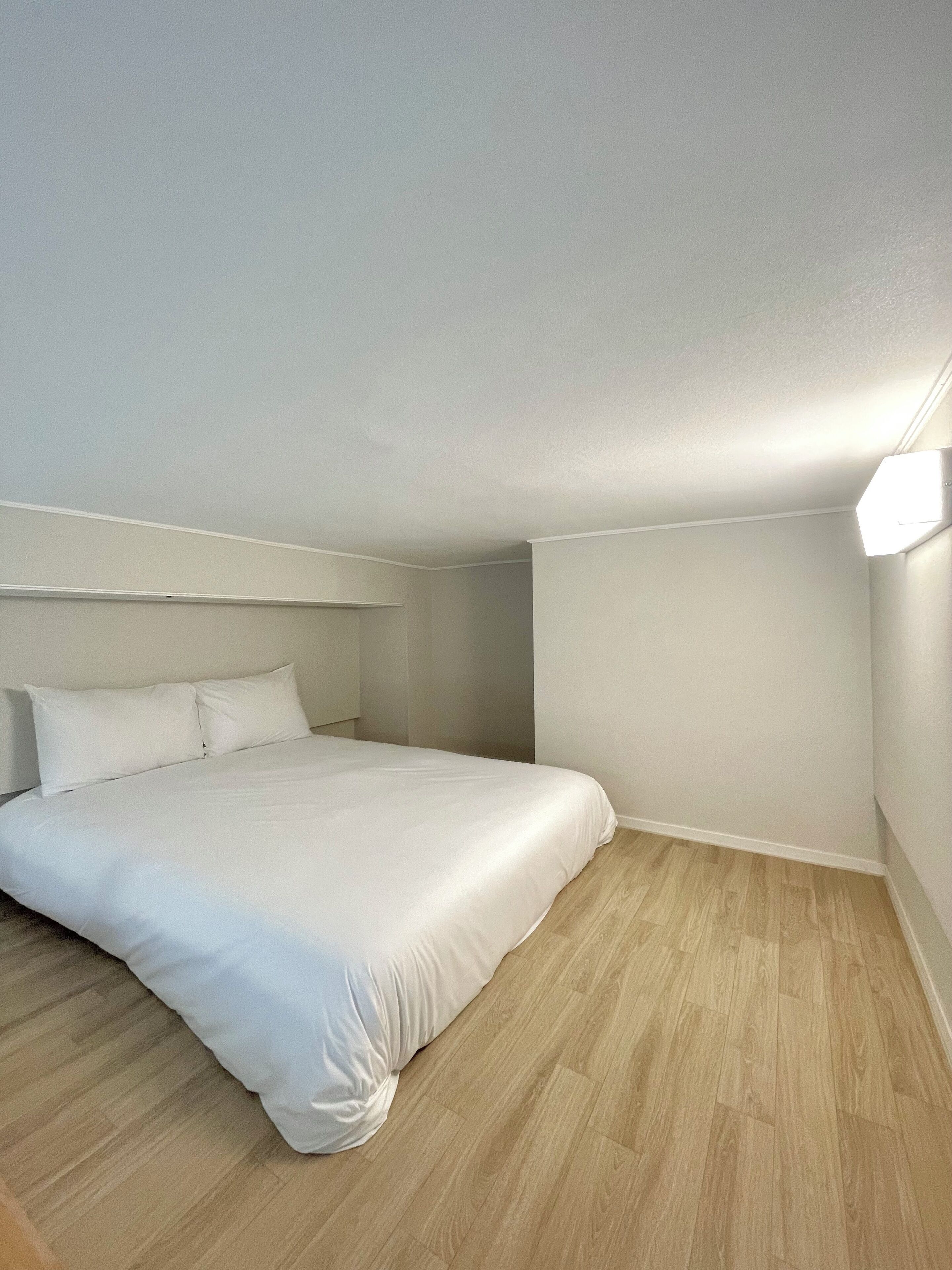 Ein Schlafzimmer mit Bett, weißen Wänden und Holzböden.