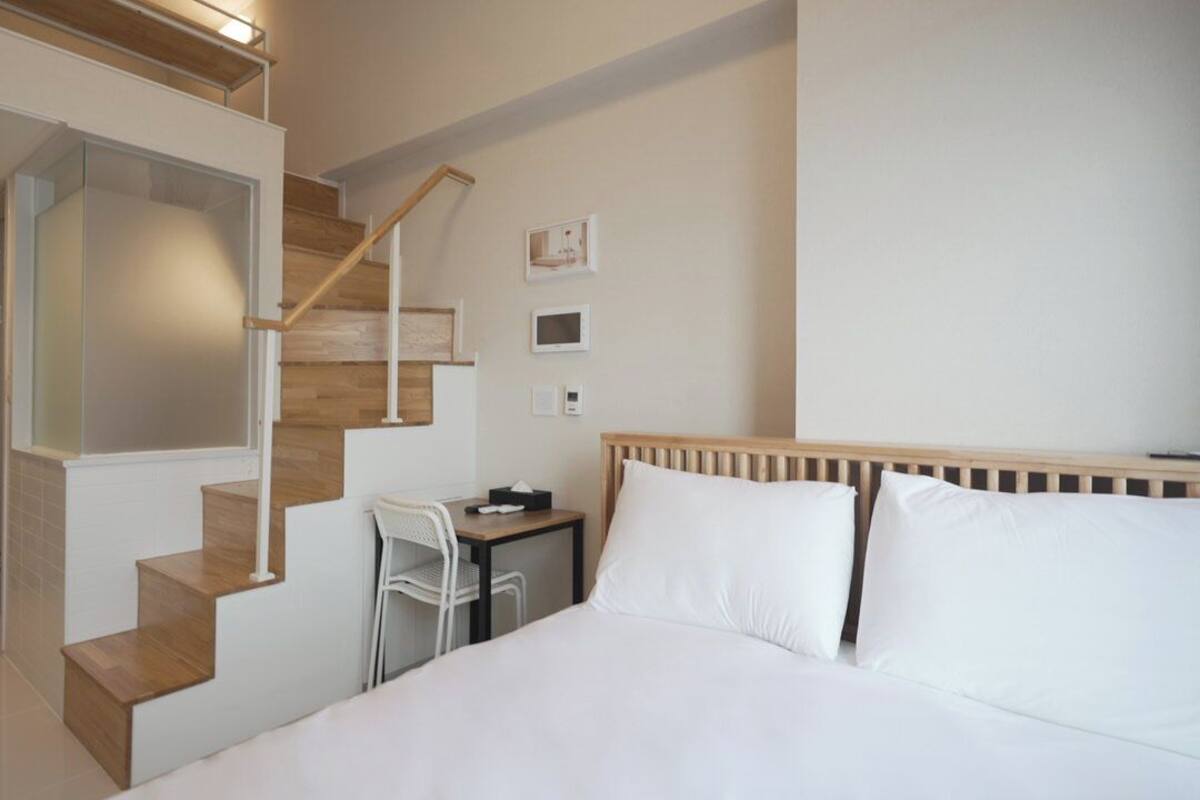 Ein Hotelzimmer mit einem Bett, einem Schreibtisch, einem Stuhl und einer Treppe.