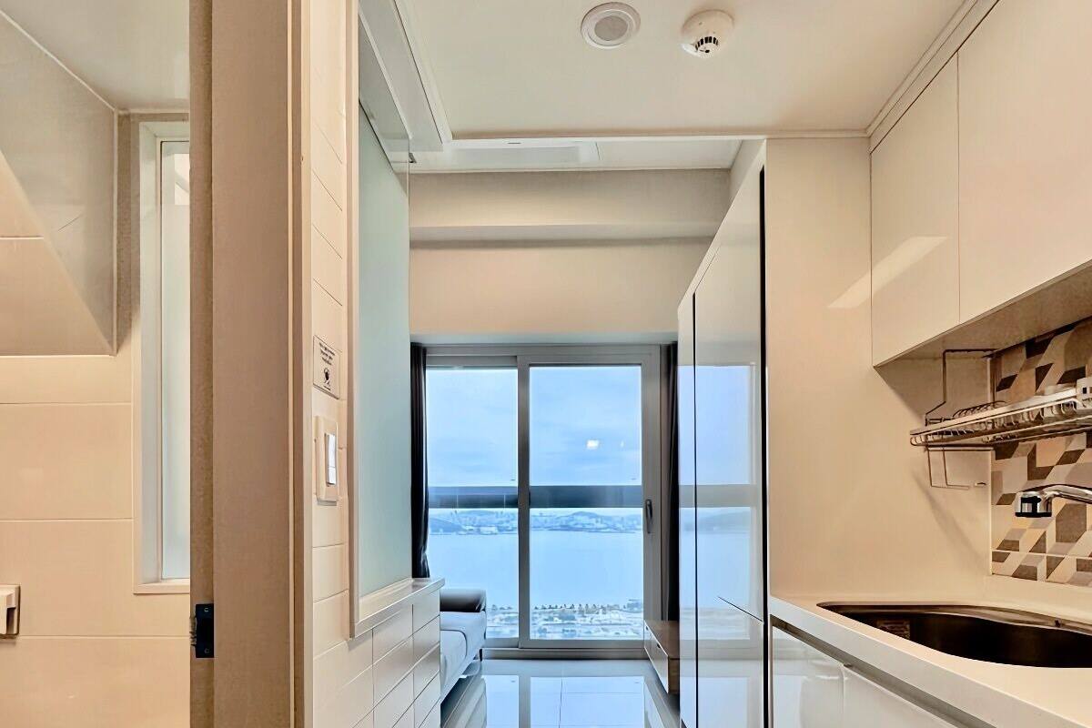 Eine moderne Küche mit Blick auf ein Gewässer, einem Balkon und einer Schiebetür zum Wohnbereich.