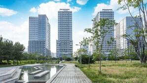 Een modern stedelijk gebied met hoge gebouwen, een centraal waterpartij en omliggend groen.
