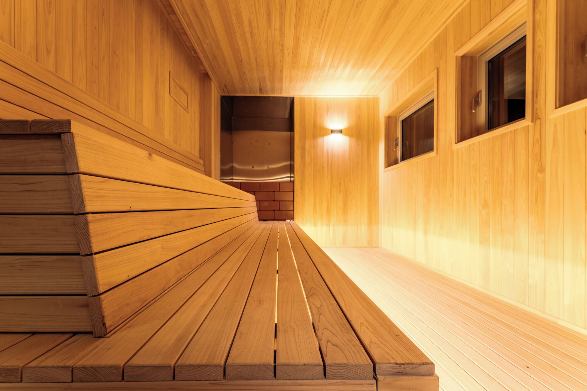 A wooden sauna with benches and a tiled floor.