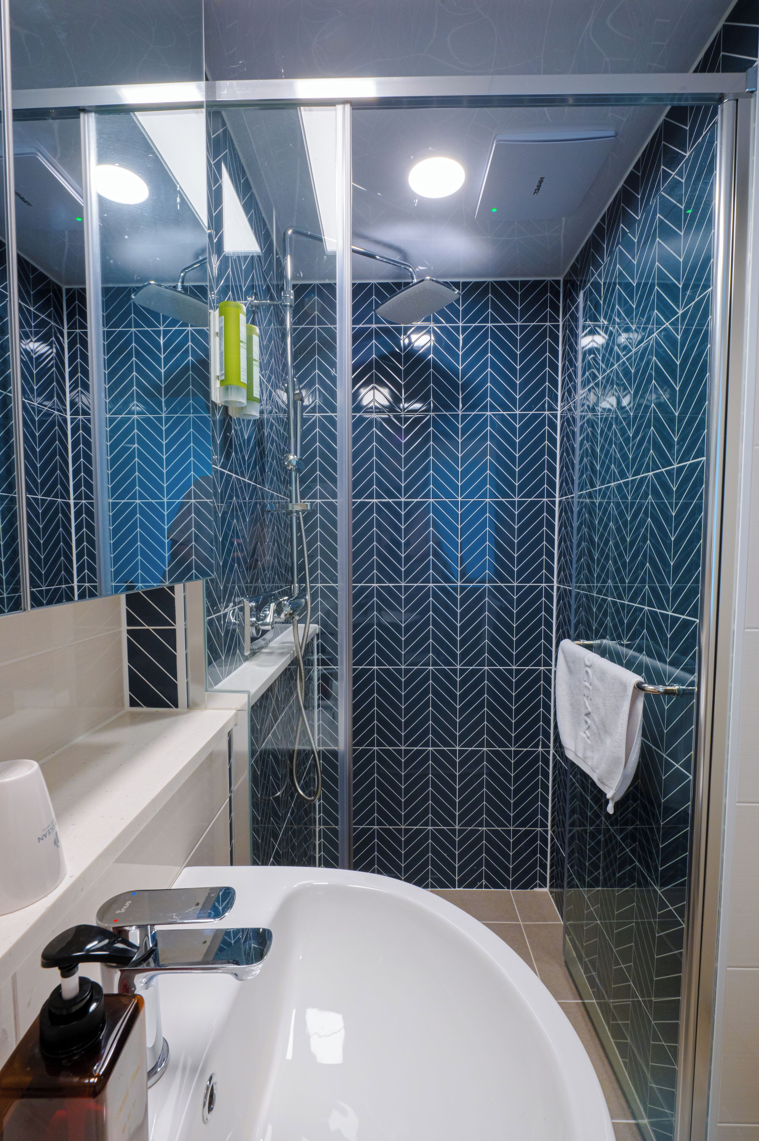 A modern bathroom with a glass-enclosed shower, a white bathtub, and a vanity with a mirror.