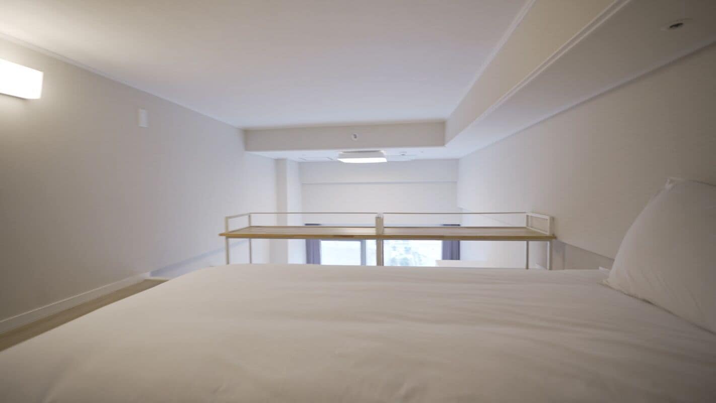 A bedroom with a bunk bed, a single bed, and a small window.