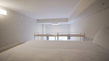 A bedroom with a bunk bed, a single bed, and a small window.