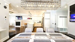 Una cucina moderna con mobili bianchi, un'isola centrale e un lampadario importante.