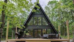 Eine moderne Hütte mit großer Terrasse, integriertem Grill und gemütlicher Sitzecke.