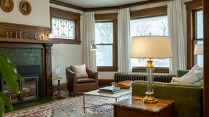 A cozy living room with a fireplace, green and red patterned rug, and a green armchair.