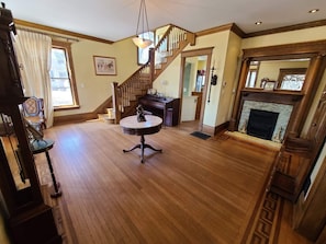 A spacious living room with a wooden staircase, a fireplace, and a round table with a statue.