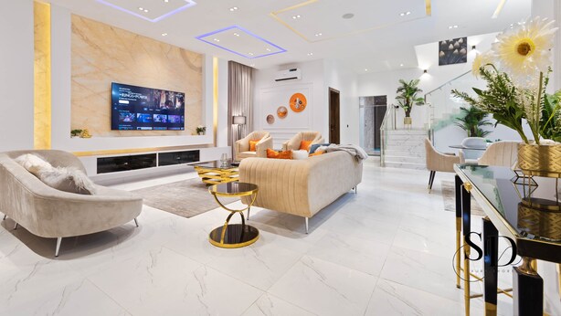 A modern living room with a sofa, armchairs, a TV, and a dining area with a glass table. -  Luxury 5 Bed Home with Swimming Pool, PS 5 Game,Snooker & Table Tenins in Lekki (Lekki)