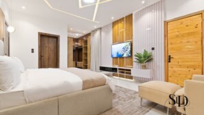 A modern bedroom with a large bed, a TV mounted on the wall, and a wooden wardrobe. -  Luxury 5 Bed Home with Swimming Pool, PS 5 Game,Snooker & Table Tenins in Lekki (Lekki)