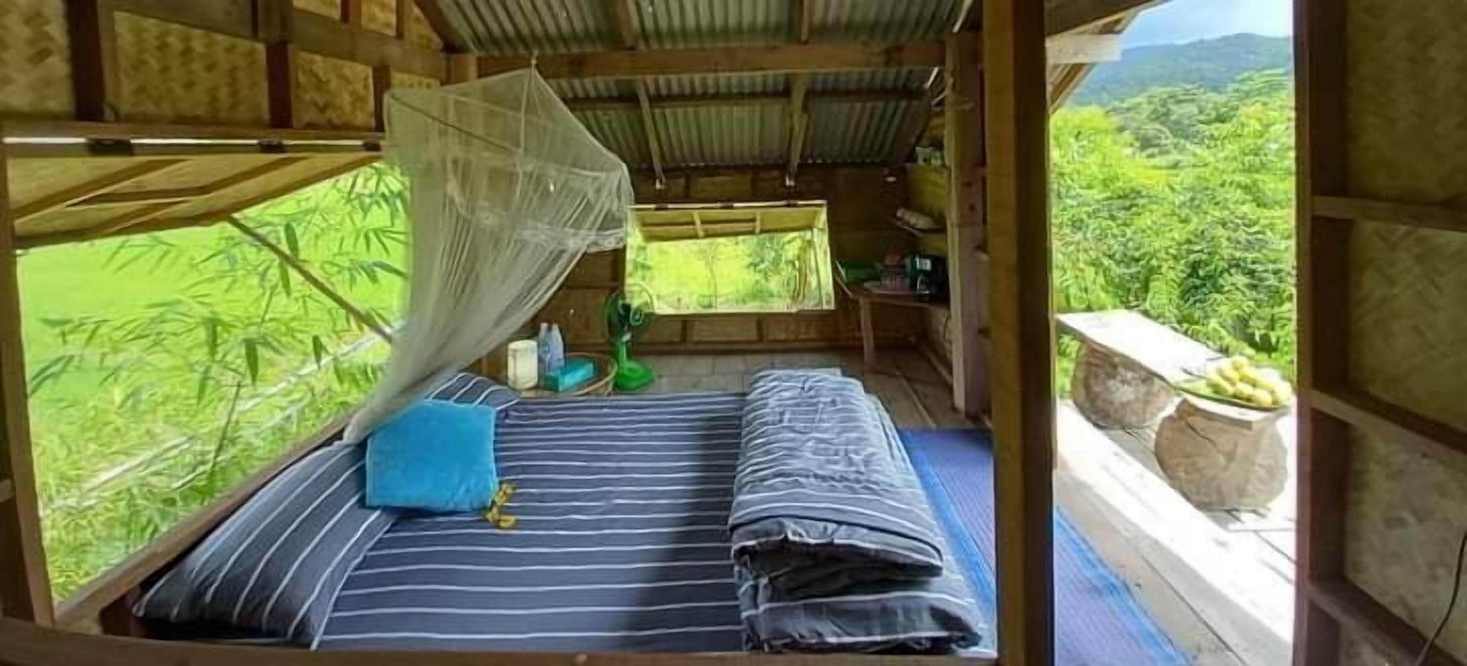 Una habitación con cama, mosquitera y vistas al verdor.