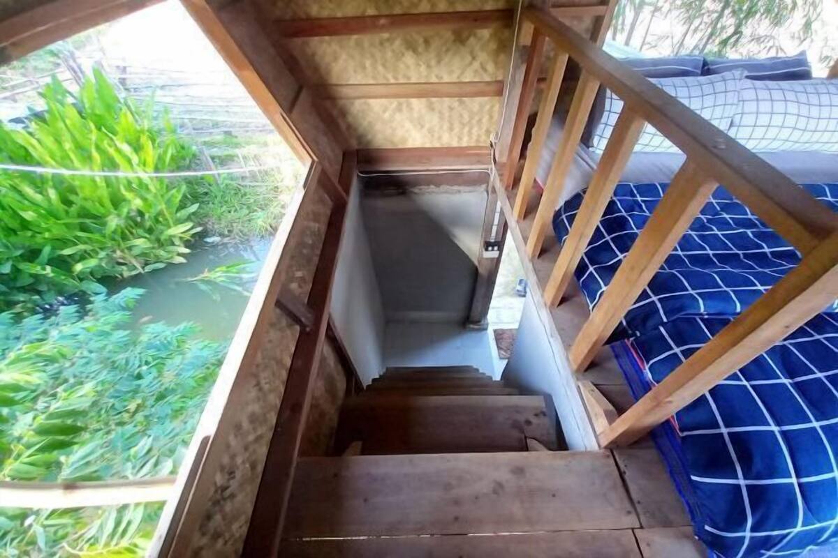 A wooden staircase leading to a room with a blue checkered bedspread.