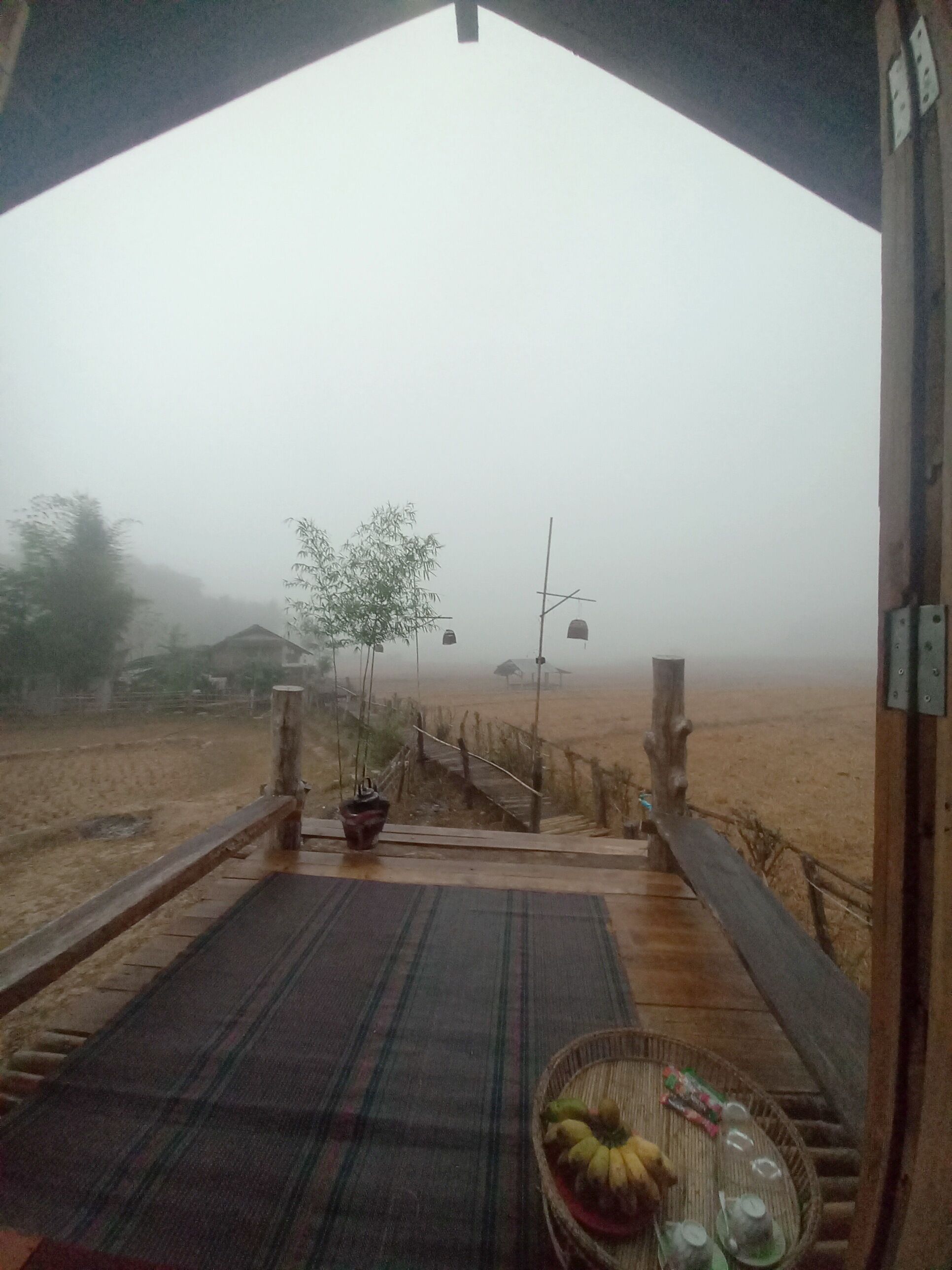 Una terraza de madera rústica con vistas a un paisaje brumoso.