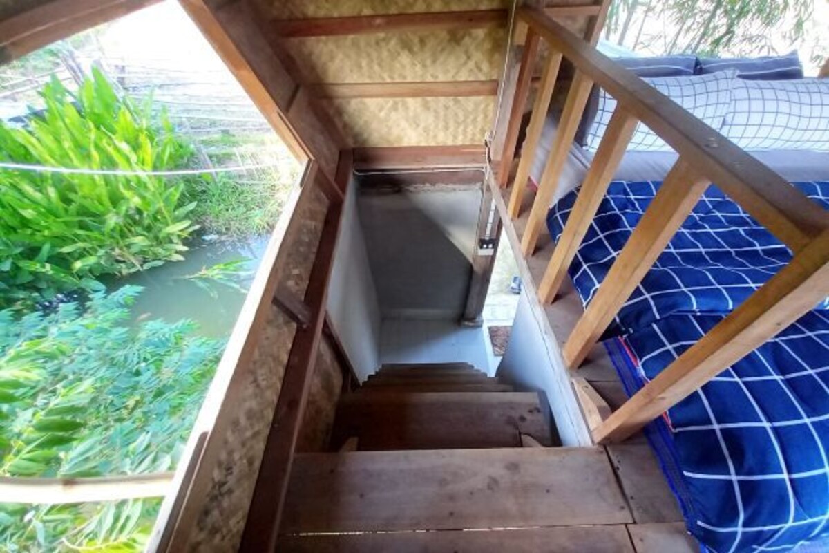 A wooden staircase leading to a room with a blue checkered bedspread.