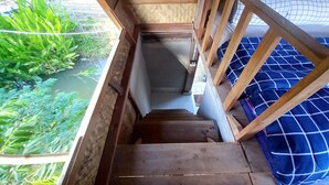 A wooden staircase leading to a balcony with a view of greenery and a water body. - Chinopuu Hut Homestay  (Chiang Dao)
