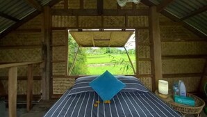 A room with a bed, a window with a view of a green landscape, and a mosquito net above the bed. - Chinopuu Hut Homestay  (Chiang Dao)