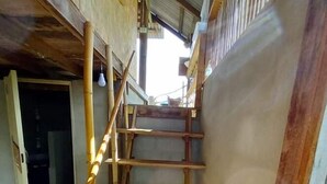 A wooden staircase leading to an upper level, with a metal railing on the right. - Chinopuu Hut Homestay  (Chiang Dao)