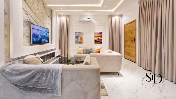 Ein modernes Wohnzimmer mit einer Couch, einem Couchtisch und einem an der Wand befestigten Fernseher.