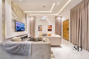 A modern living room with a sofa, a coffee table, and a TV mounted on the wall. - Luxury 4 Bed House with Swimming Pool + PS5 Game + Snoker+Table Tennis in Lekki (Lekki)