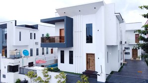 Ein modernes, mehrgeschossiges Gebäude mit Flachdach, großen Fenstern und einem Balkon im zweiten Stock.