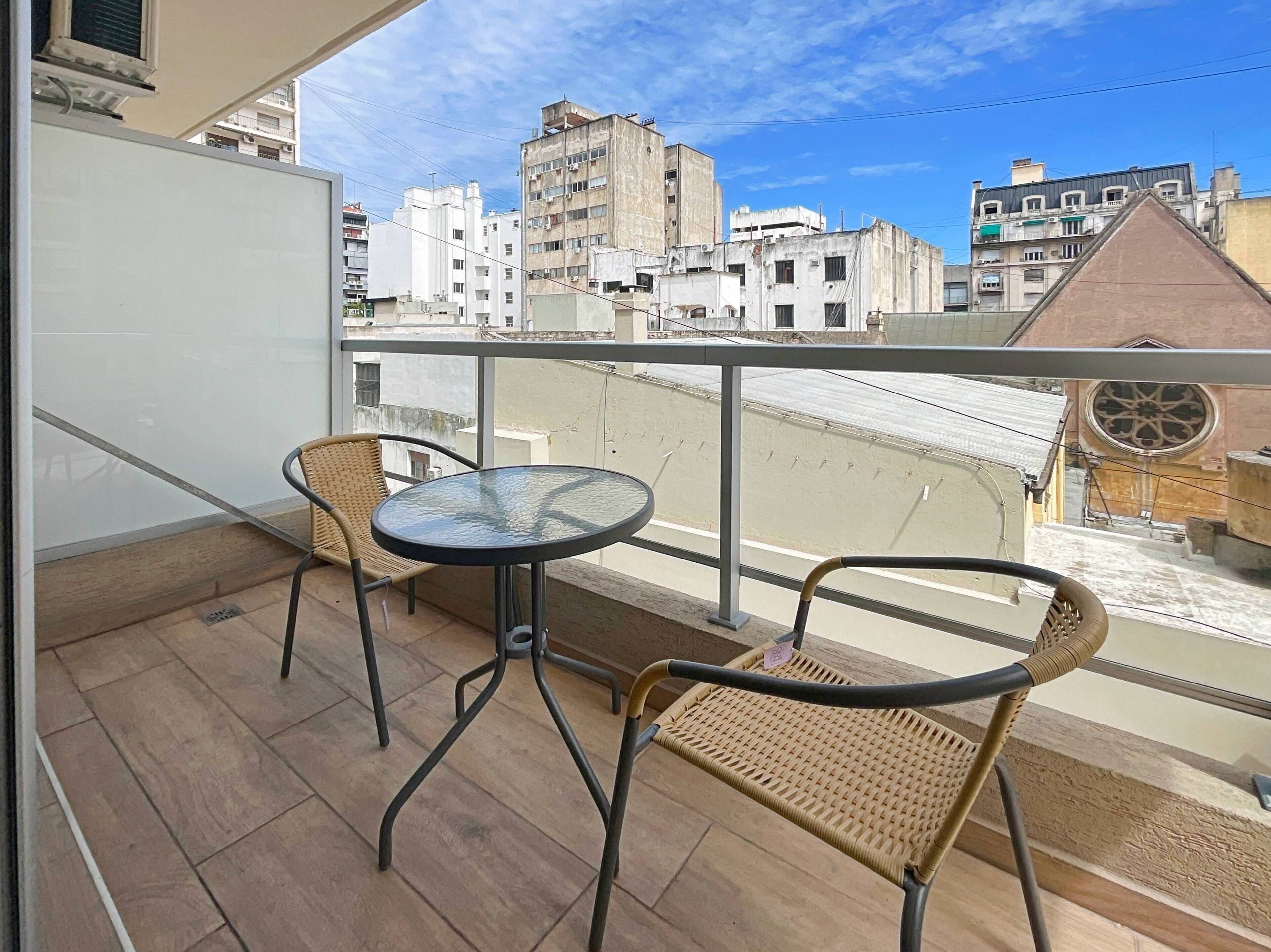 A balcony with two wicker chairs and a small round table.