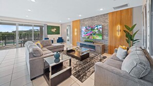 A modern living room with a large flat-screen TV, a sofa set, a coffee table, and a glass-top coffee table. - Fruit Ninja Arcade, Fast and Furious Racing, Space Bedrooms, Theater, Pool Table: Cosmic Way (Kissimmee)