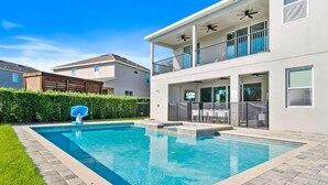 Ein modernes, zweistöckiges Haus mit Swimmingpool, Balkon und Gartenmöbeln sowie einem gepflegten Rasen.