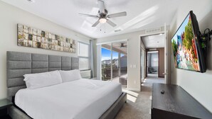 Ein Schlafzimmer mit einem großen Bett, einem Deckenventilator, einem Fernseher und einem Balkon mit Blick.