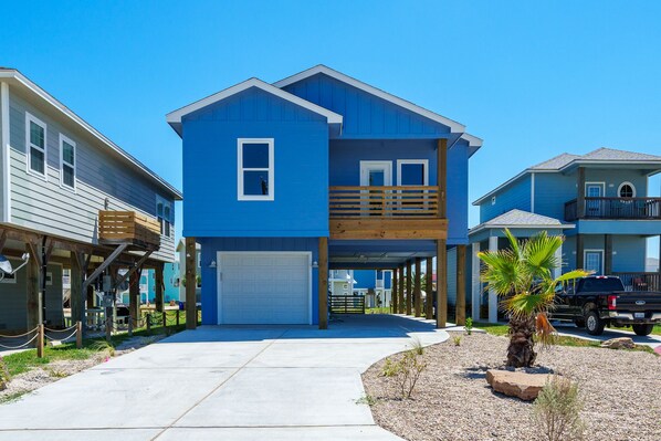 A two-story house with a blue exterior, a garage, and a wooden deck.