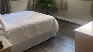 Quarto com cama, planta em vaso e janela com cortinas.