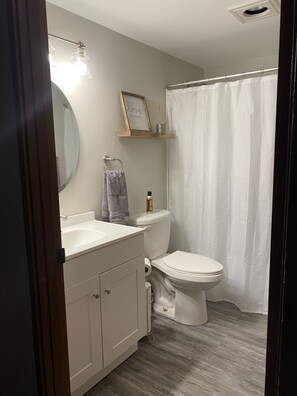Een badkamer met toilet, wastafel, spiegel en douchegordijn.