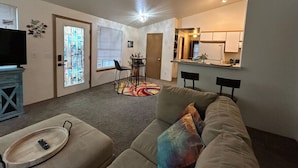 A living room with a sofa, a TV, and a dining area with a table and chairs. - Clyde's Crib: Cozy Ms. Pac-Man (Boise)