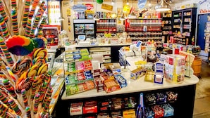 A candy store with shelves of sweets, a checkout counter, and a variety of candy brands. - Clyde's Crib: Cozy Ms. Pac-Man (Boise)