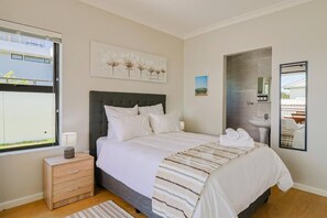 A bedroom with a bed, bedside table, lamp, and artwork.