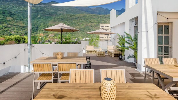 Une terrasse extérieure avec des tables et des chaises en bois, des parasols et des plantes en pot.