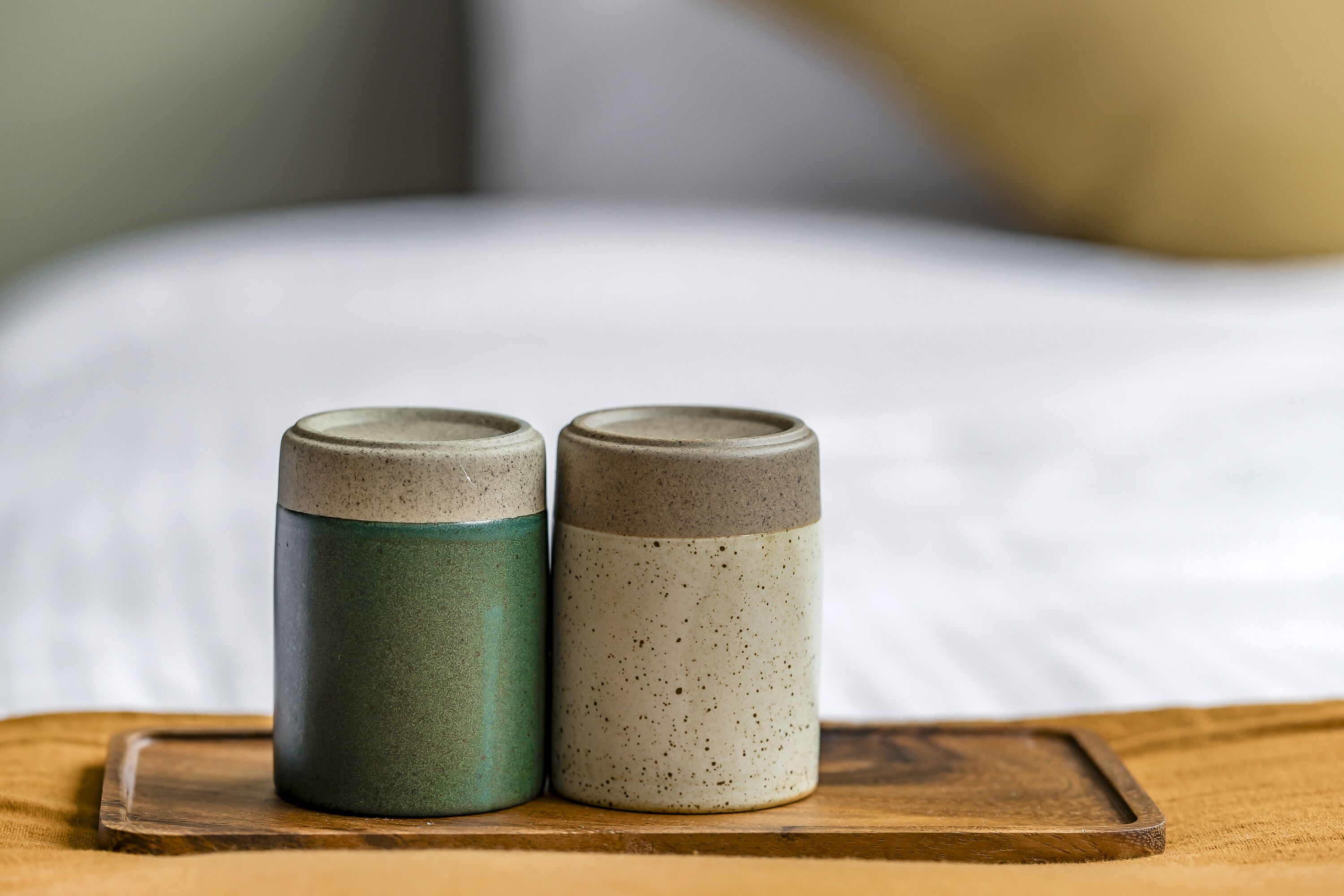 Two ceramic containers on a wooden tray.