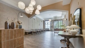 Une pièce spacieuse avec une longue table en bois, de nombreuses chaises et des lanternes en papier suspendues.