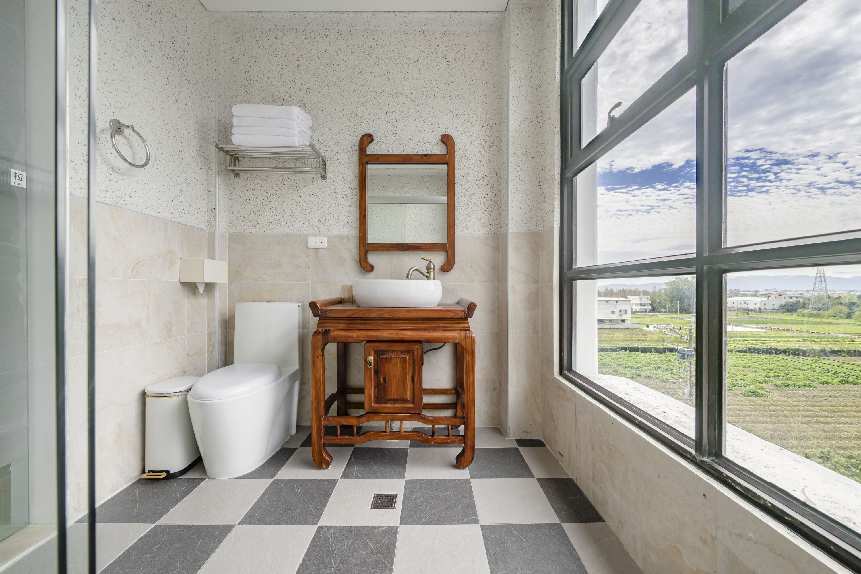A bathroom with a checkered floor, a wooden vanity with a mirror, a toilet, and a sink.