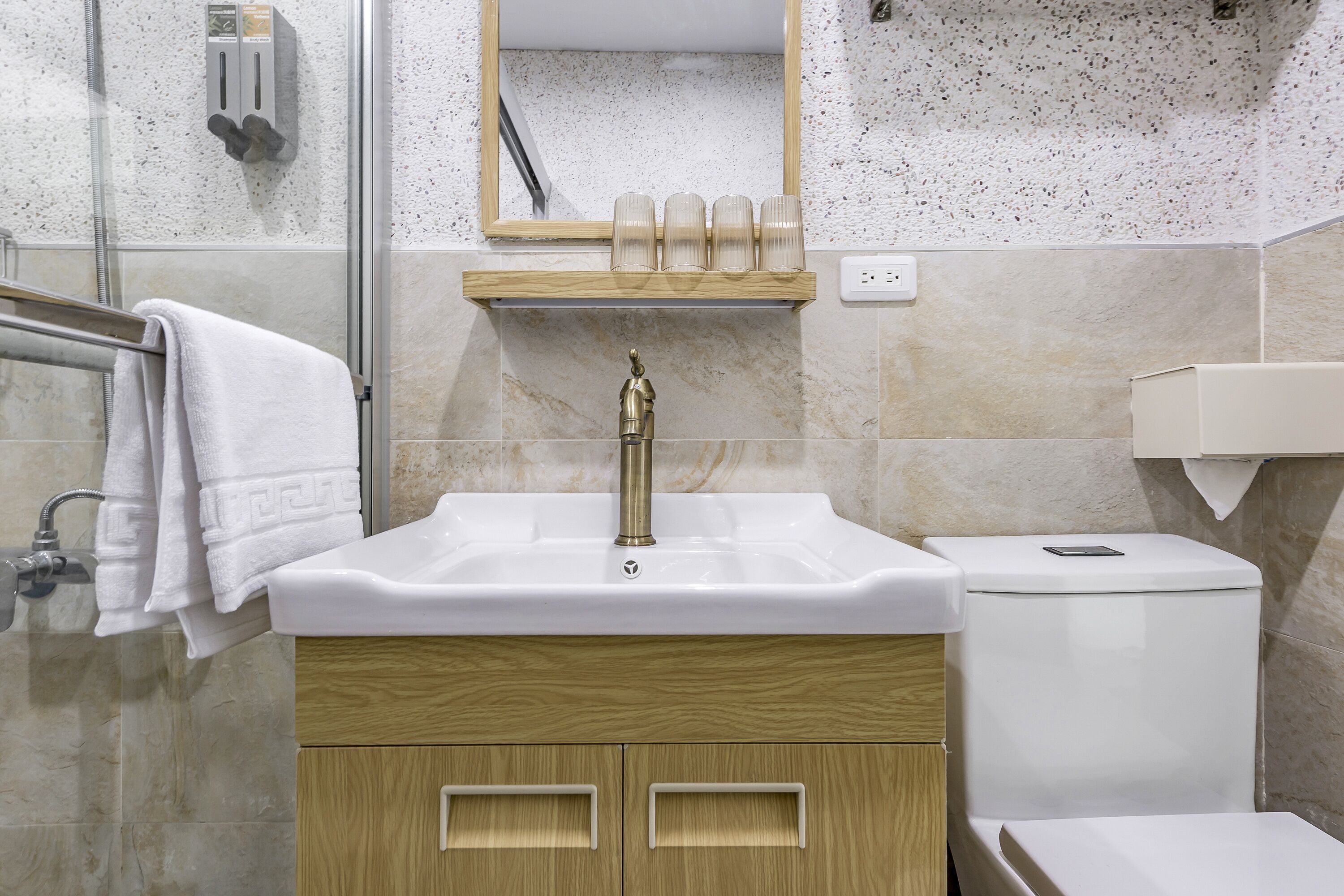 Une salle de bain avec un lavabo blanc, des toilettes et une douche à parois de verre.