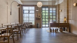 A spacious dining area with high tables and chairs, a large window with a view, and a traditional-style wall with decorative elements. - Kuma B&B (Ji'an)