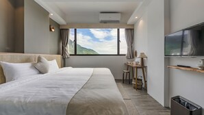 Une chambre d’hôtel moderne dotée d’un grand lit, d’un bureau avec une chaise, d’une télévision et offrant une vue sur les montagnes.