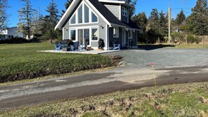 Uma casa de dois andares com varanda, área de estar externa e entrada por um caminho de pedras.