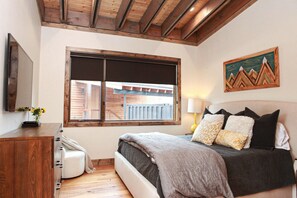 Une chambre à coucher avec un lit, une fenêtre, un tableau et un plafond en bois.