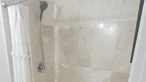 Un baño con ducha, inodoro y piso de baldosas.