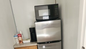 Una cocina compacta con un refrigerador de acero inoxidable, un microondas y un armario de madera.