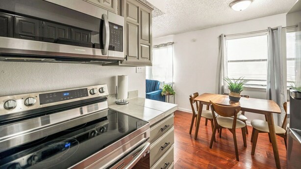 A modern kitchen with stainless steel appliances, wooden cabinets, and a dining area with a table and chairs.