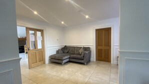 A spacious living area with a grey sectional sofa, a wooden door, and a tiled floor. - Rostrevor Valley 6-Br, Sleeps 20 w/ Hot Tub & View (Rostrevor)